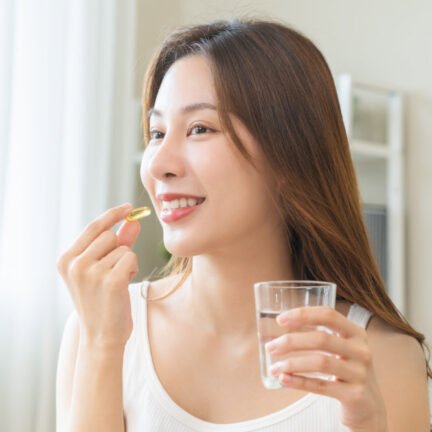 Dietary supplement, asian young woman, girl hand holding medical pill capsule, take or eat vitamin C, D for treatment for skin, hair and nail strengthen with glass of pure water at home, healthcare.